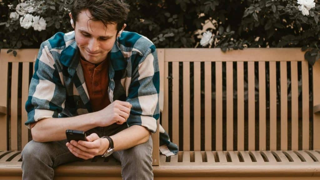 A person sitting on a bench looking at a phone.