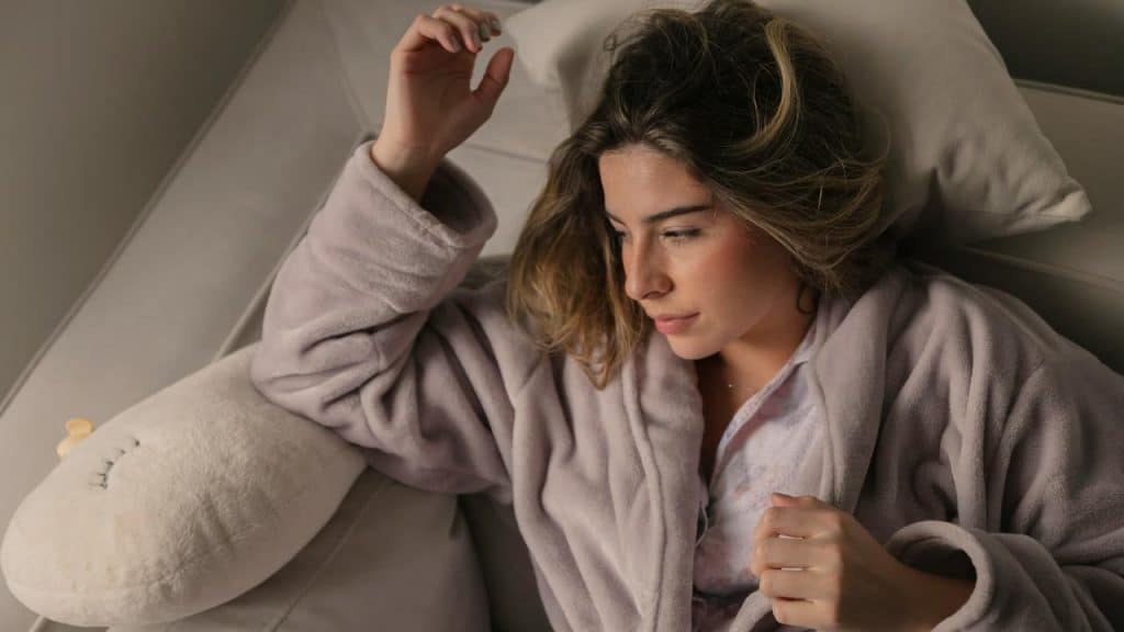 A woman lying on a couch wearing a robe.