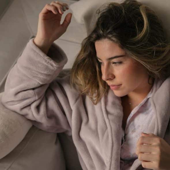 A woman lying on a couch wearing a robe.