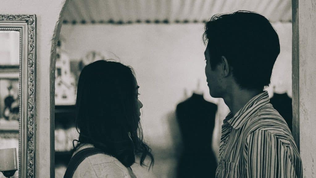 A man and woman standing in grayscale photography.