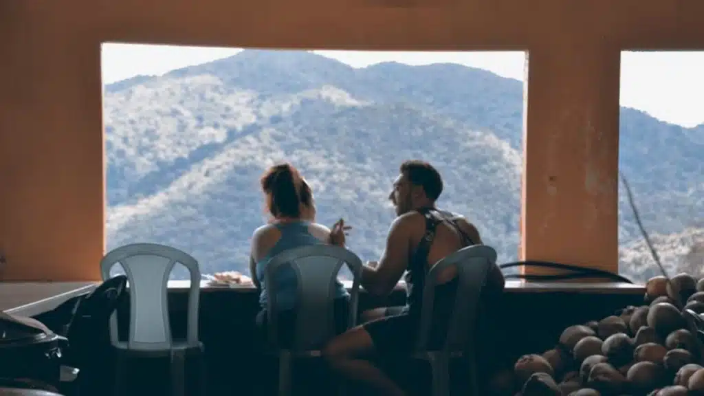 Couple on a date with a man distracted, gesturing about past relationships