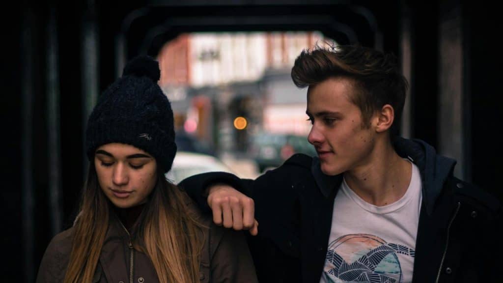 A young couple walking together under a covered walkway.
