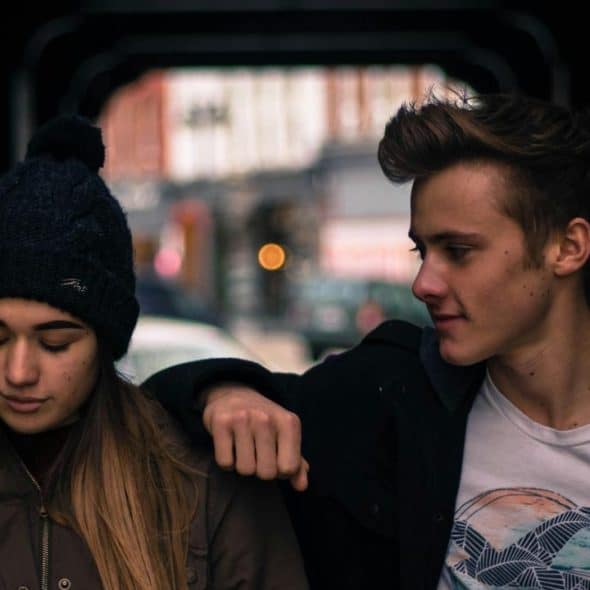 A young couple walking together under a covered walkway.