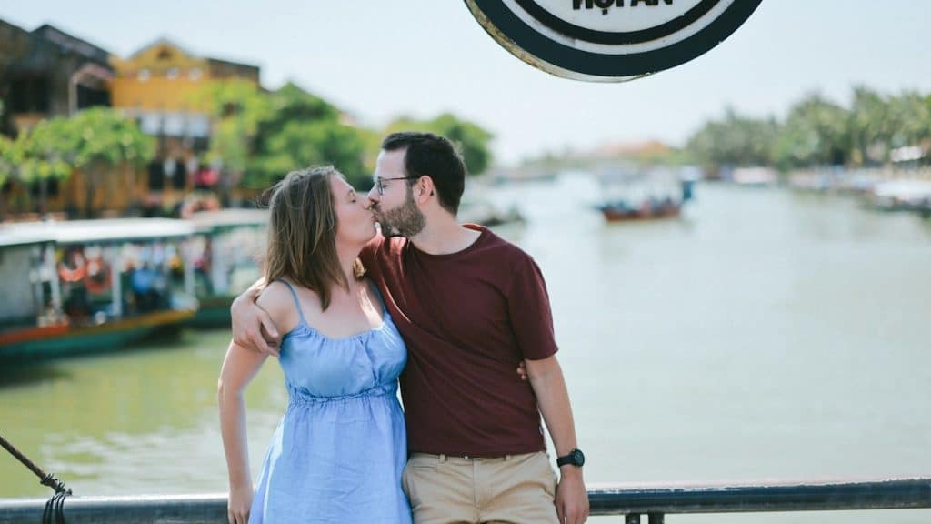 A couple kisses by a river.