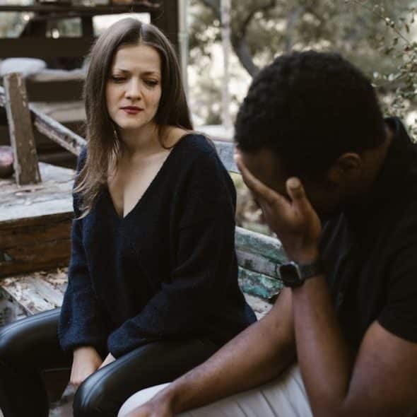Distressed couple sitting outside on a bench.
