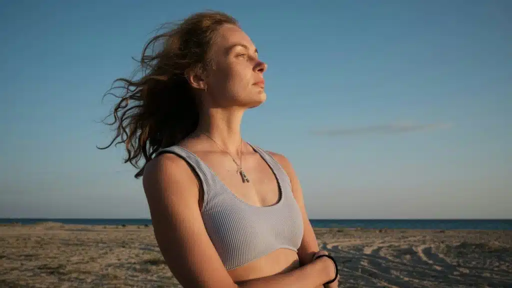 A woman standing on a beach with her arms crossed.