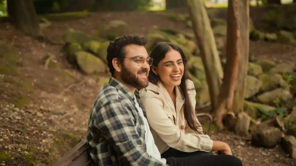 A man and a woman sitting on a bench and smiling together.