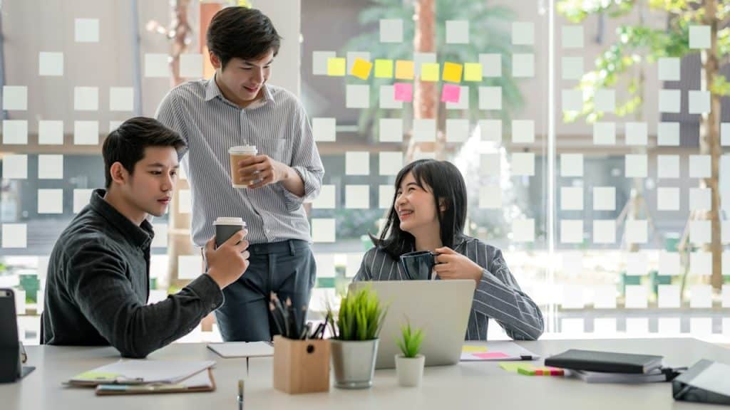 A group of people talking and having coffee while sitting in an office.