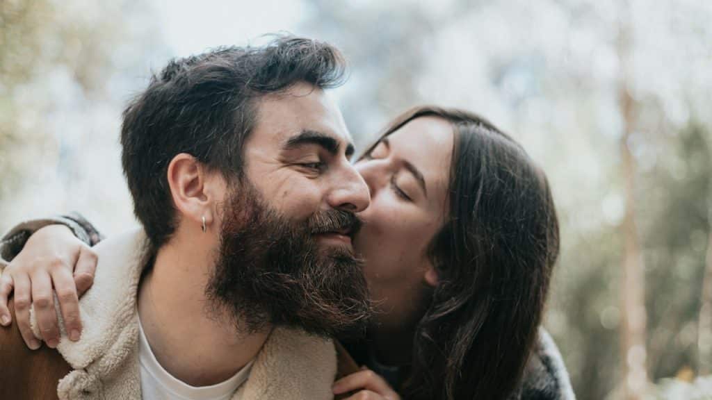 A man and a woman kissing in the woods.
