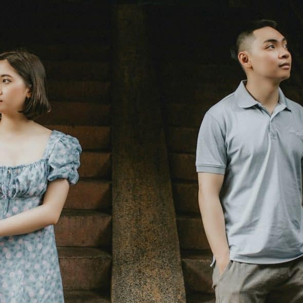 A man and a woman standing next to each other but looking away from each other.