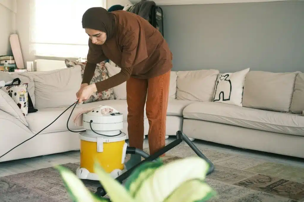 A woman using a vacuum cleaner to clean a living room.