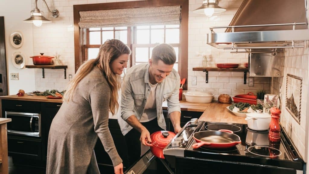 A man and a woman cooking meals in a kitchen together.