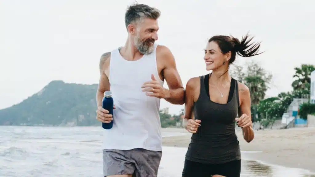 A couple jogging on a beach.