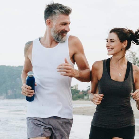 A couple jogging on a beach.