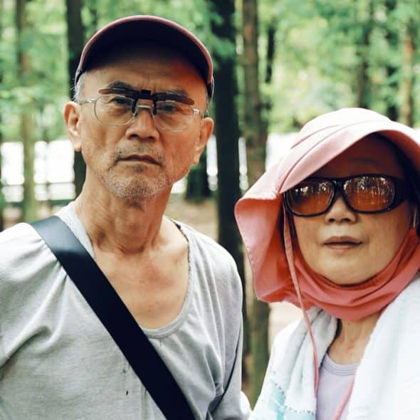 A man and a woman standing in a forest.