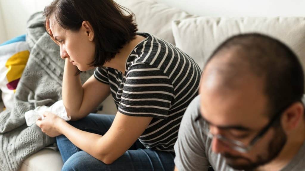 Unhappy couple sitting on a couch after a fight.