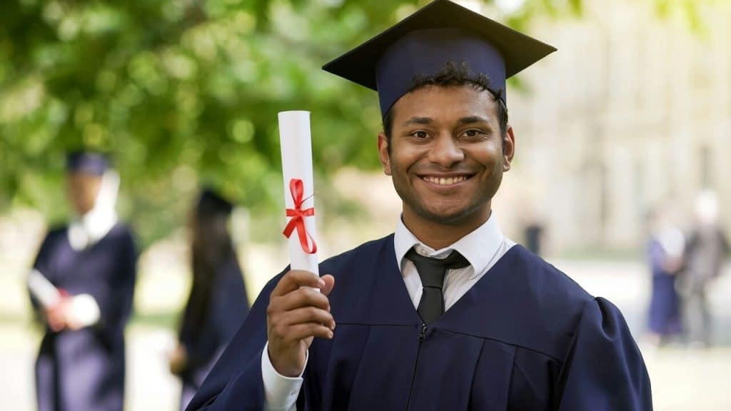 A man smiling and holding his diploma