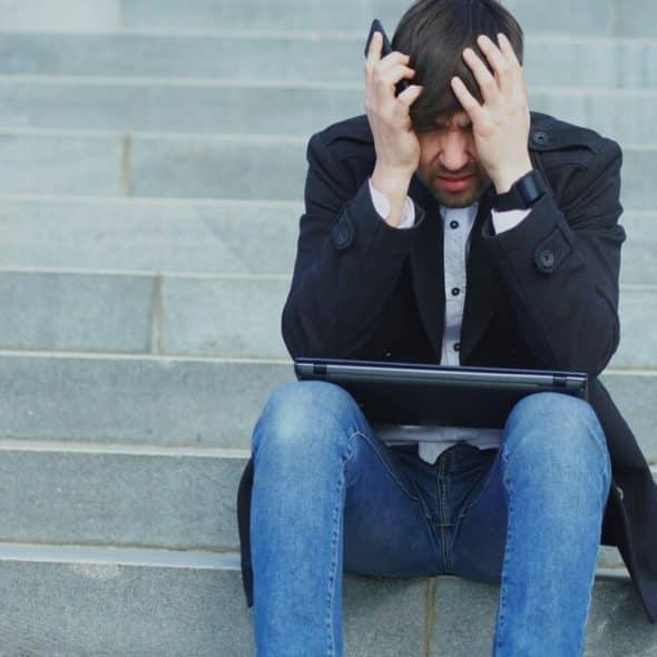 A man looking stressed with his laptop
