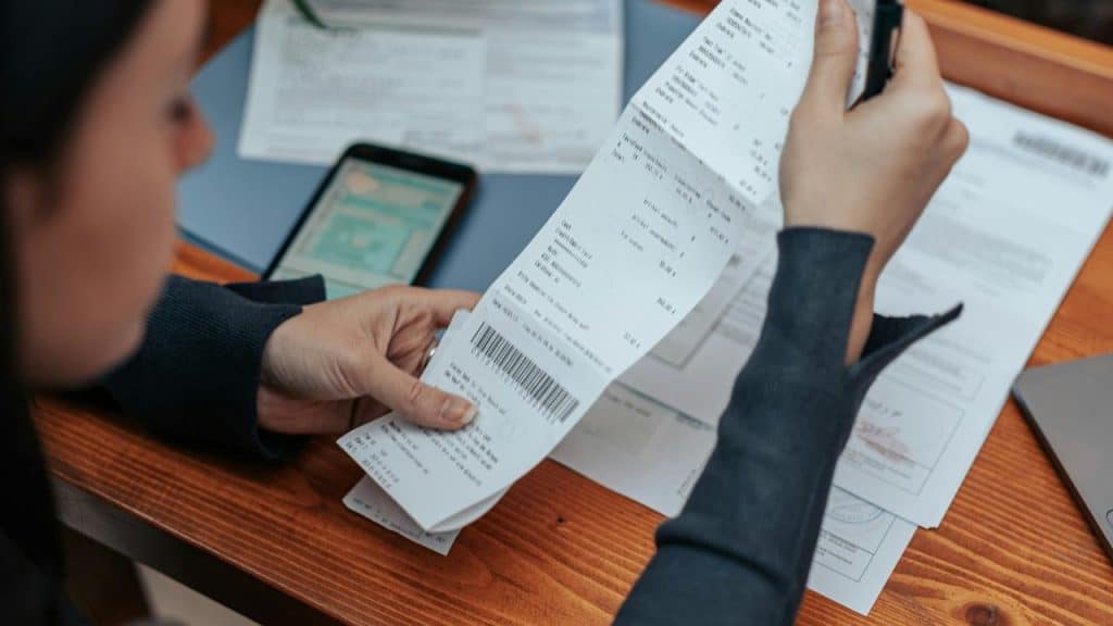 A woman reviewing bills and receipts at a desk.