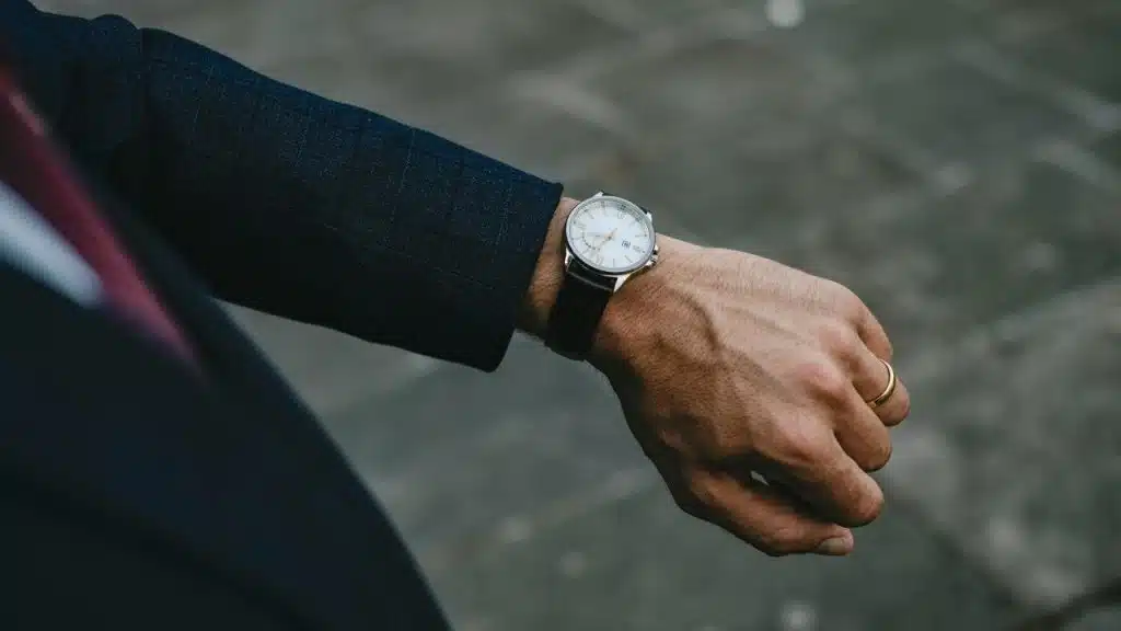 A person in a suit checking a wristwatch.