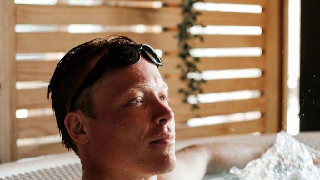 A person relaxing in a hot tub with goggles resting on their forehead.
