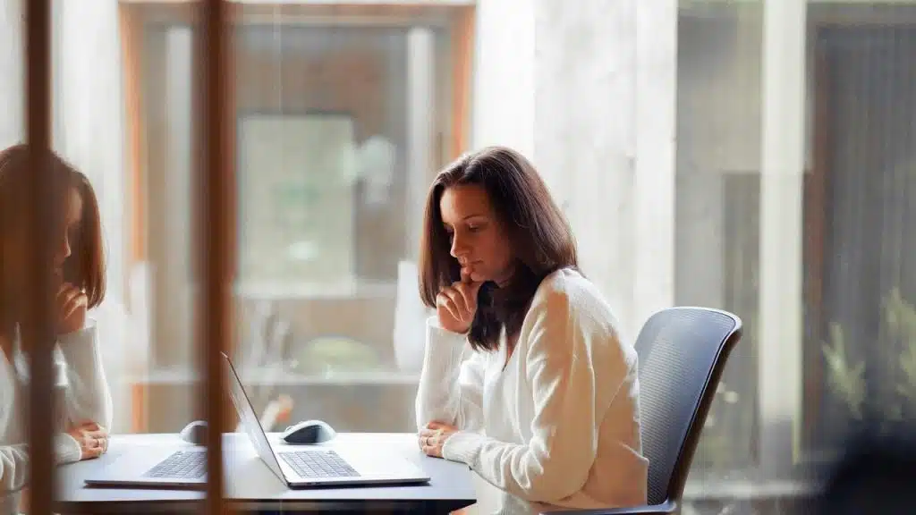 A woman works on a laptop at a desk.