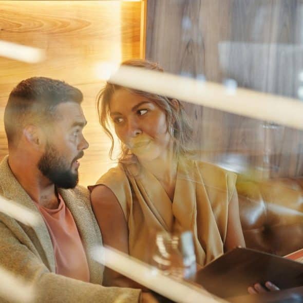 The woman holding the menu is looking at the man.
