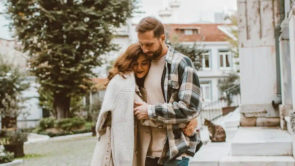A couple hugging closely while walking outdoors.