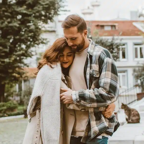 A couple hugging closely while walking outdoors.
