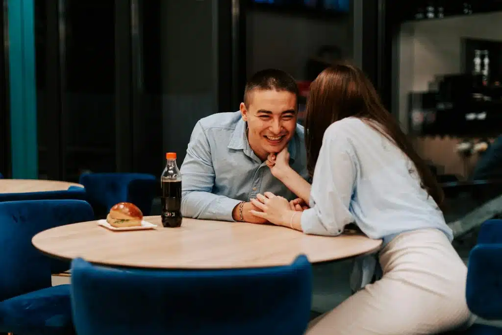 A man laughs as the woman whispers something to him.