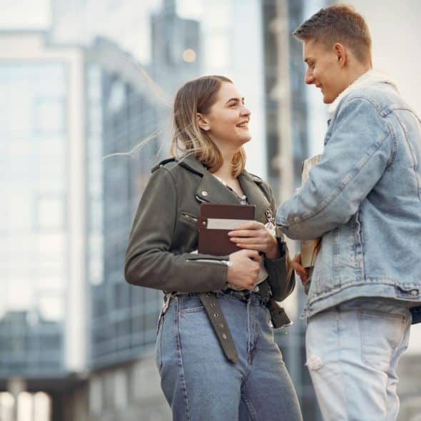 A man and a woman looking at each other while standing on the street.
