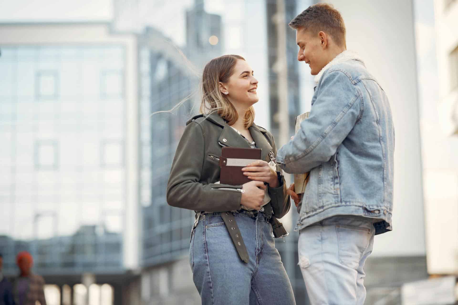 A man and a woman looking at each other while standing on the street.