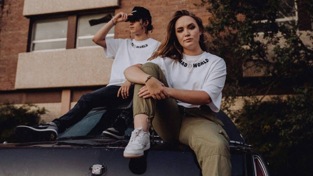 A man and woman sitting on the hood of a car.