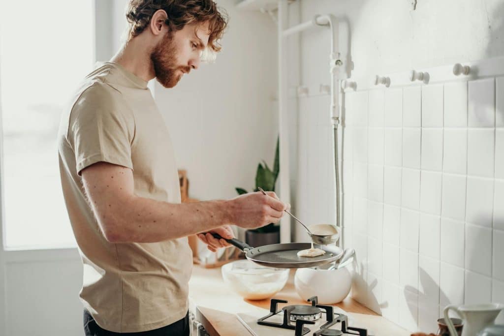 A man cooking pancakes in his kitchen.