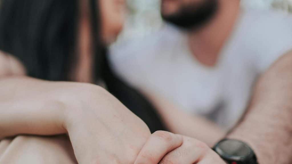 A close-up of a couple sitting together and holding hands.