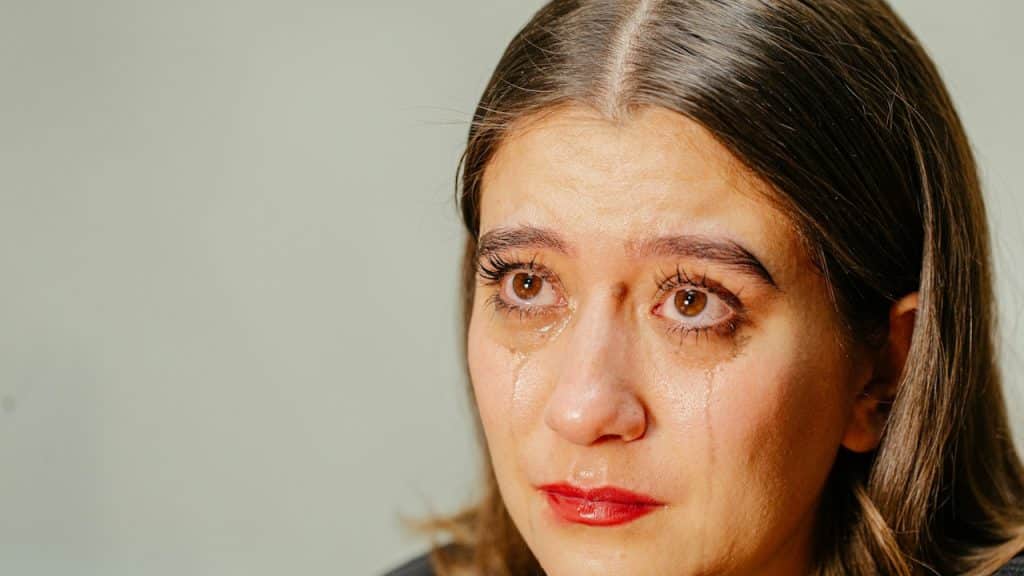 A closeup of a sad woman, tears rolling down her face.
