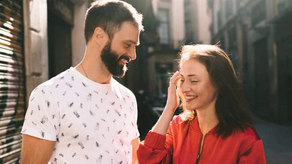 Smiling couple on a sunny street, the woman touching her hair.