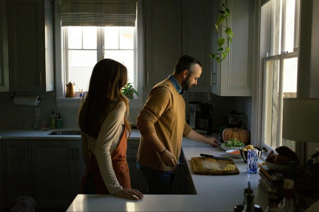 A woman watching a man preparing food