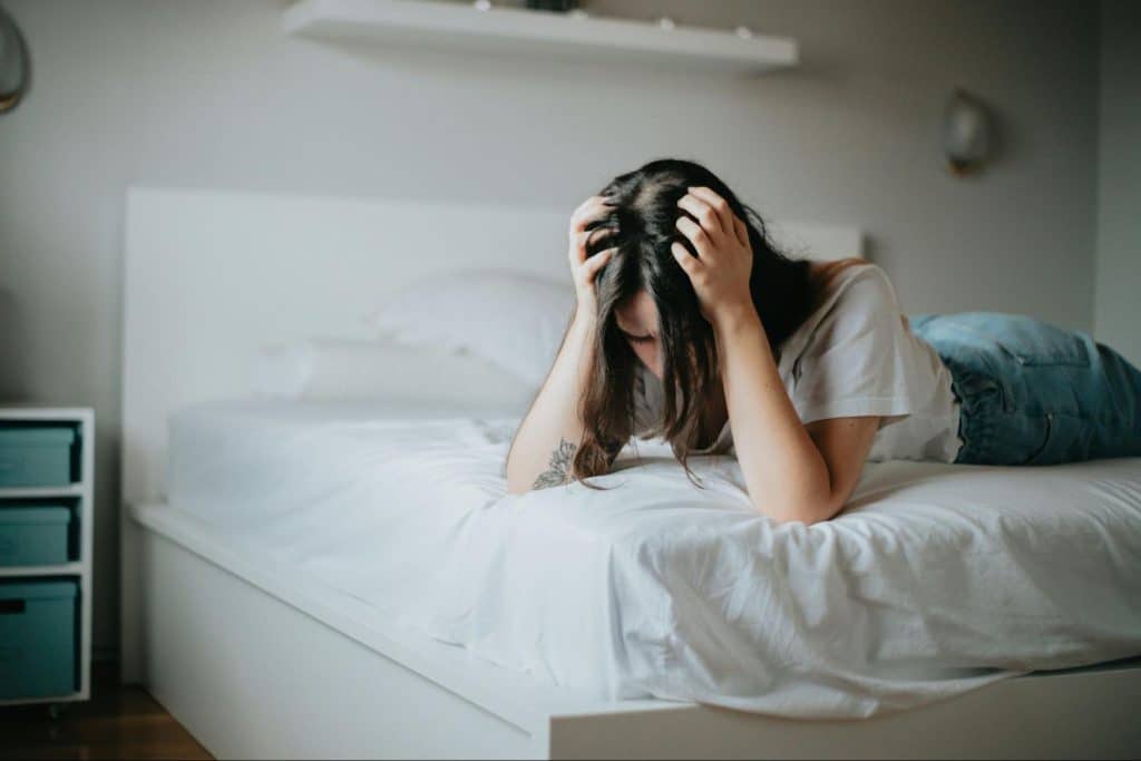A woman at the bed and holding her head