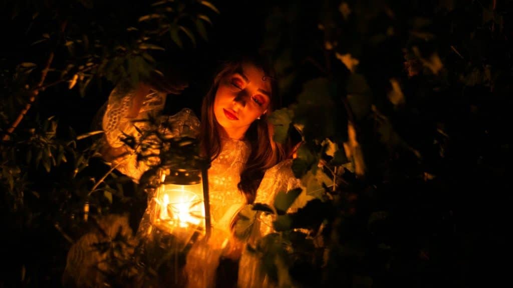 A woman holding a lantern in the dark.