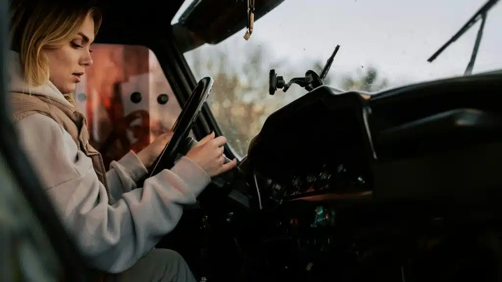 A person driving a vehicle while adjusting the dashboard controls.