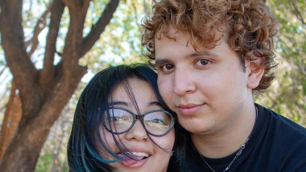 Young couple embracing outdoors under a tree.