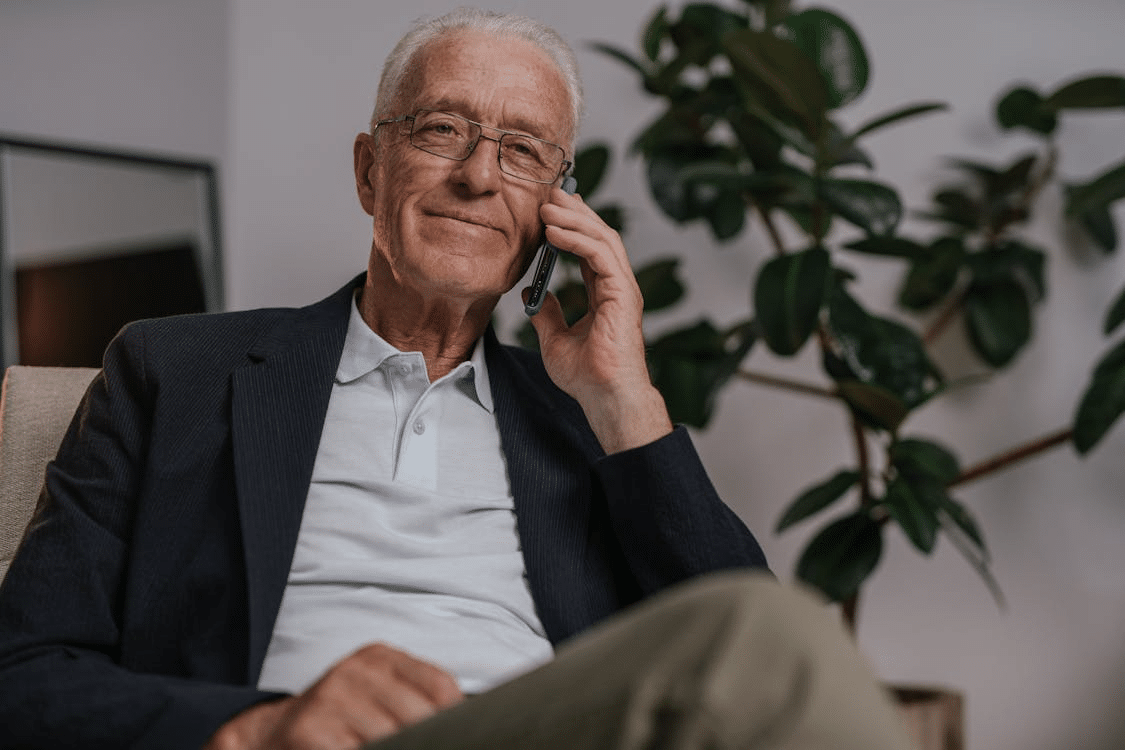 An old man smiling while on a call