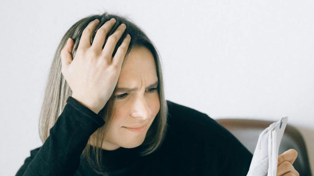 A woman holds her head while reading a document.