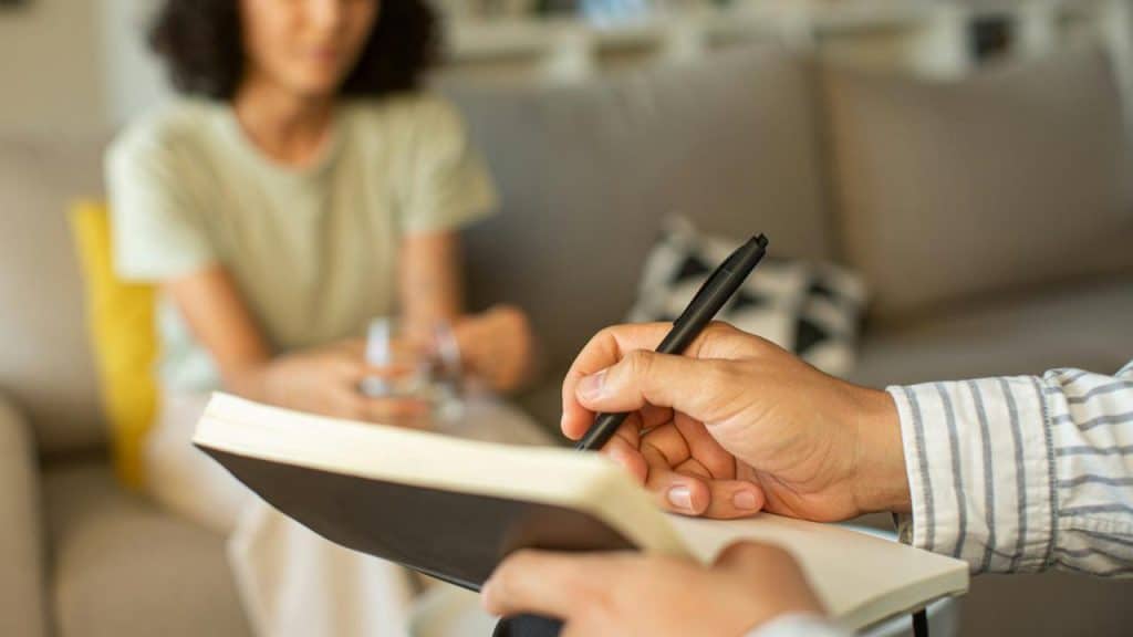 A person taking notes during a therapy or counseling session.