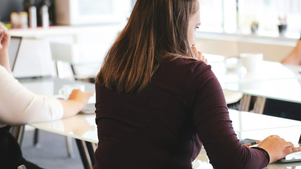 A woman sitting at a table in a bright room.