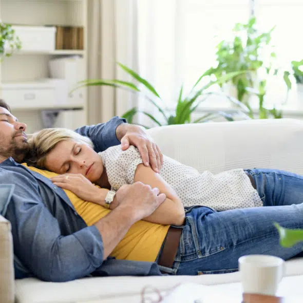 A couple sleeping together on the couch