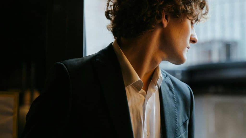 A man in a suit looks out a window.