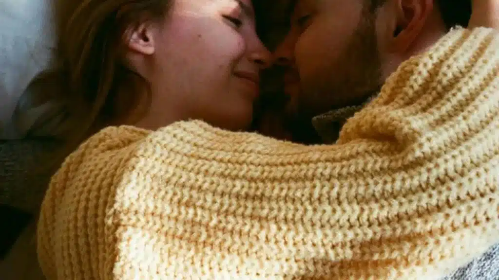 A couple lying close together, smiling and embracing warmly.