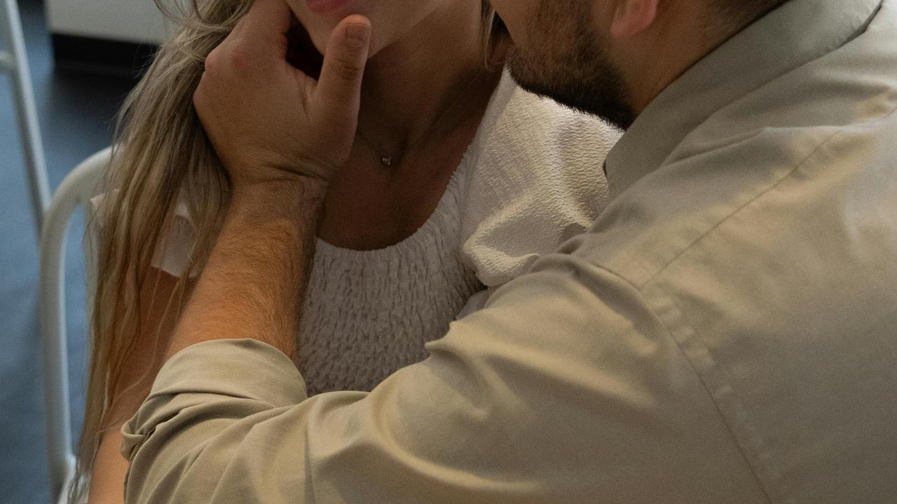 A man gently touching a woman’s face while sitting close together.